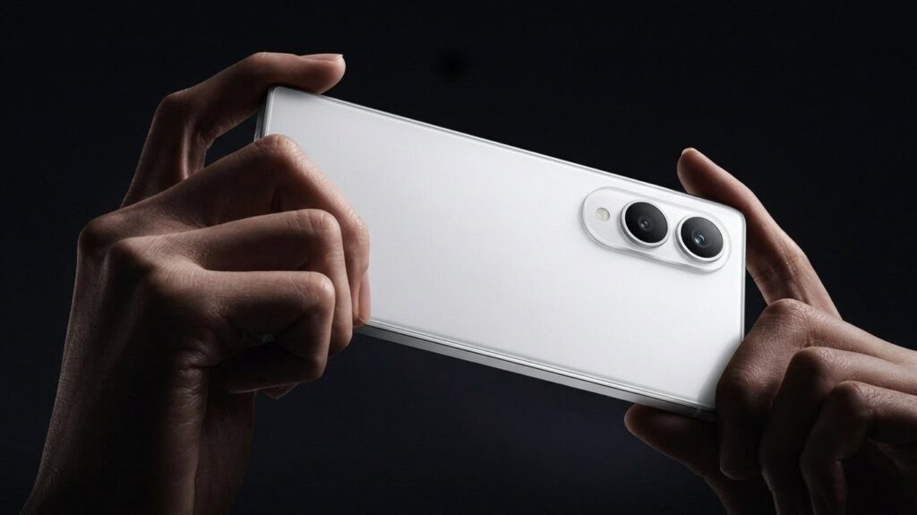 close-up shot of a person holding a sleek, matte white smartphone horizontally with both hands against a dramatic, dark background. The phone features a prominent dual-camera setup with large lenses on a raised oval module.